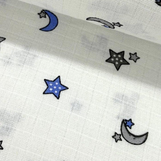 Close up of cotton double gauze muslin fabric patterned with night blue and grey stars and moons on a white background.