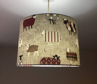 Fabric drum ceiling lampshade with sheep pattern on a plain background.
