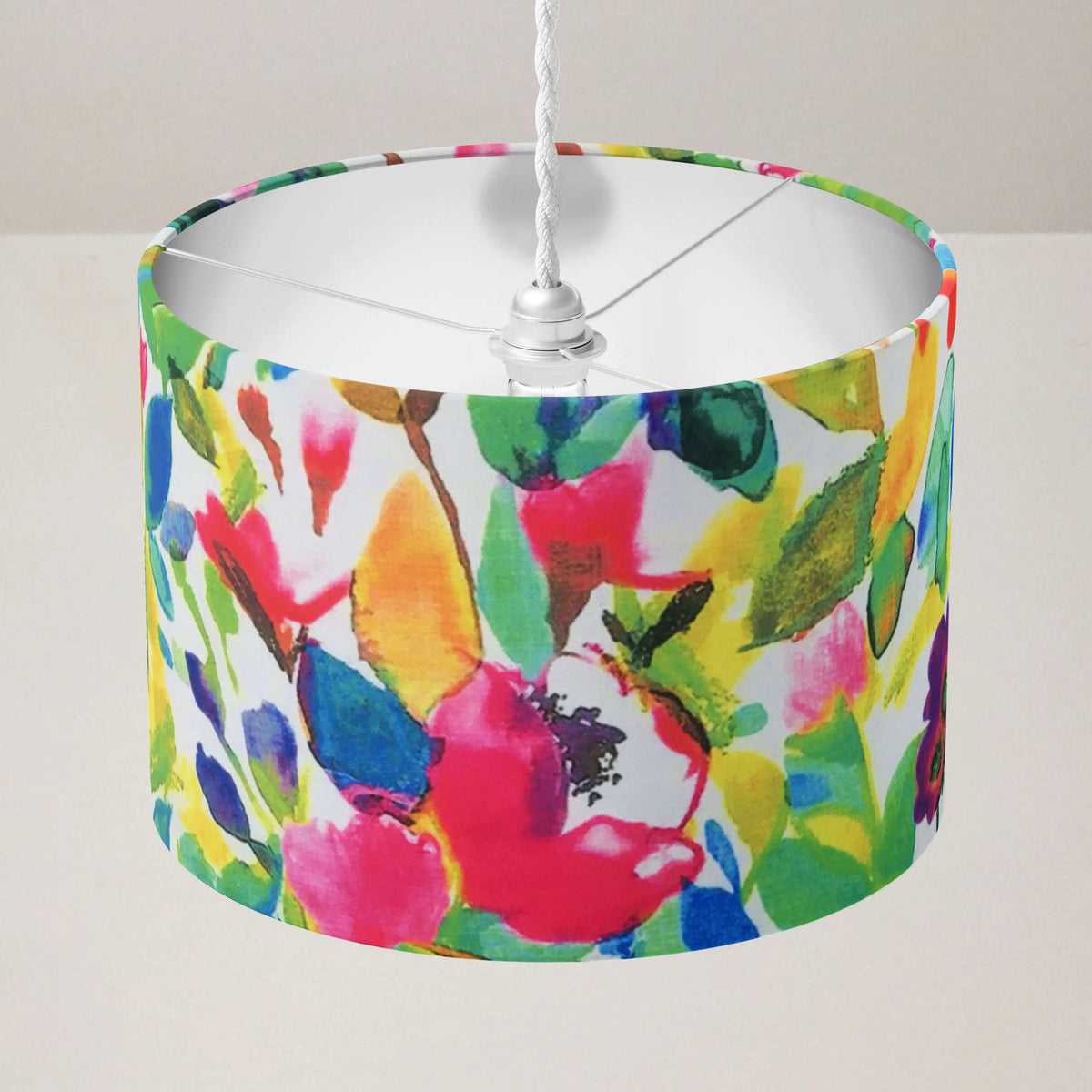 Colorful floral-patterned boho ceiling lampshade in pink green yellow blue on a plain background.