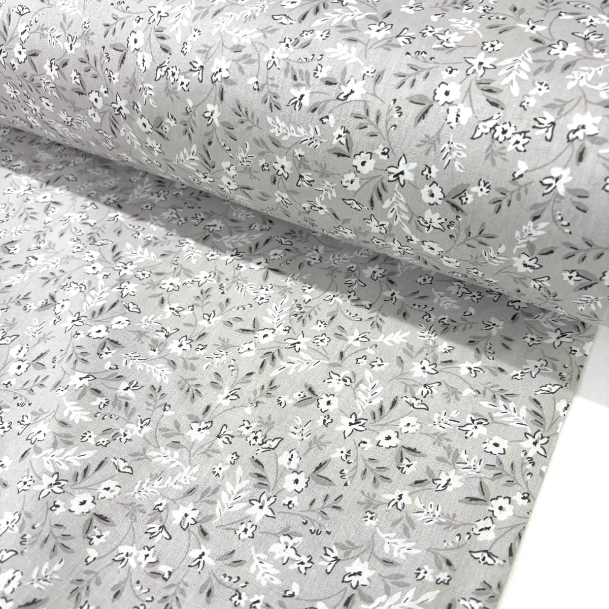 Floral patterned fabric with small white flowers on a beige background.