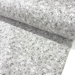Floral patterned fabric with small white flowers on a beige background.