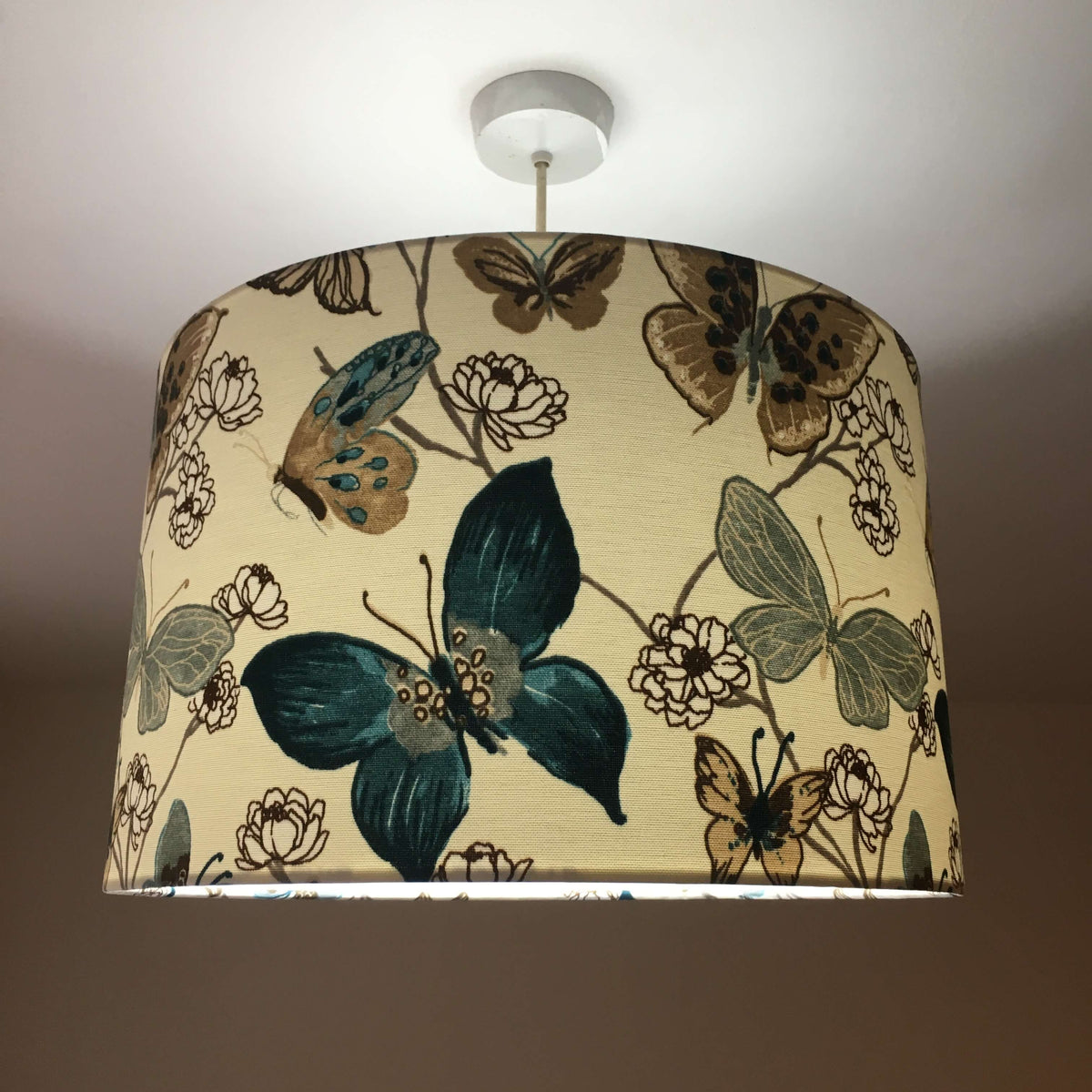 Decorative lampshade with tropical butterflies and flowers pattern on a plain background.