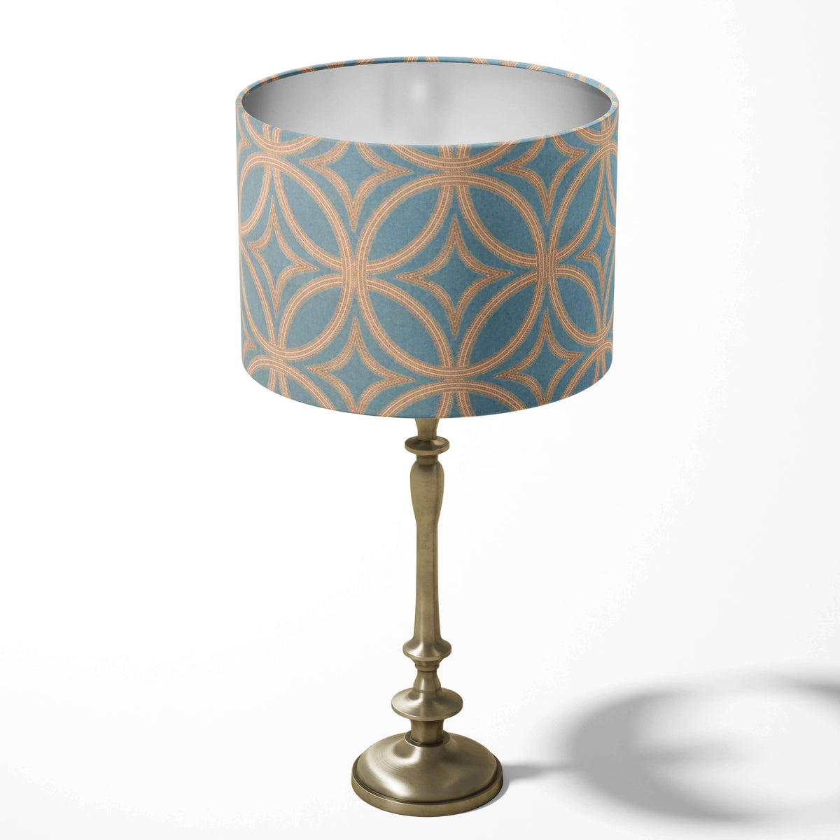 Table lampshade with a teal blue and gold mid century pattern on a white background.