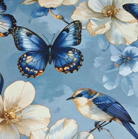 Close-up of blue floral upholstery fabric printed with bluebirds, white magnolia flowers and navy butterflies.