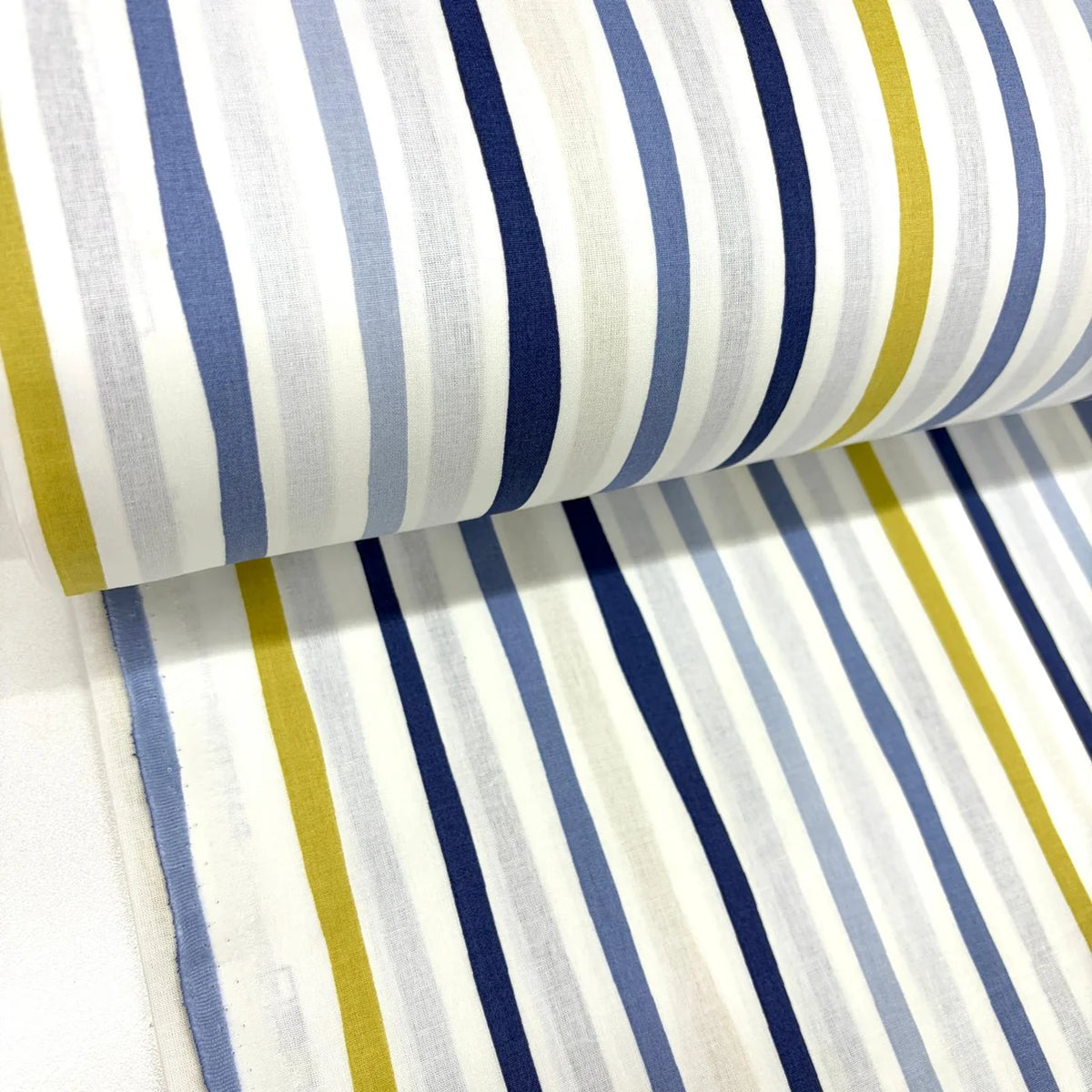 Blue, navy, and mustard abstract striped cotton fabric on a white background, ideal for quilting, dressmaking, patchwork and sewing projects.
