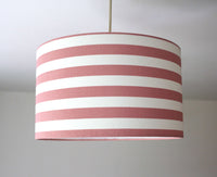 A blush pink and white striped pattern drum ceiling lampshade.