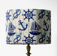 Table lampshade with nautical pattern featuring anchors, ropes, boats and wheels on a white background.
