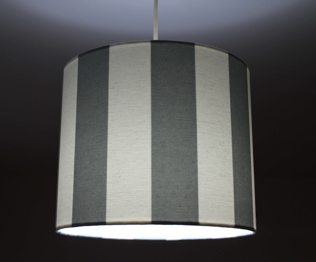 Striped lampshade with gray and white vertical stripes on a dark background.