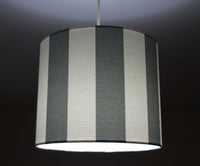 Striped lampshade with gray and white vertical stripes on a dark background.
