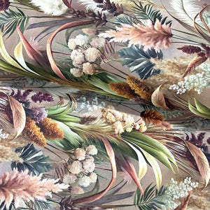 Botanical cotton fabric featuring pampas grass, tropical leaves and dried floral stems in neutral green, cream and blush tones on a taupe background.