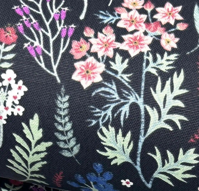 Upholstery fabric with pink, purple and blue wild flowers and light green leaves on black background.