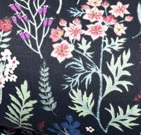 Upholstery fabric with pink, purple and blue wild flowers and light green leaves on black background.
