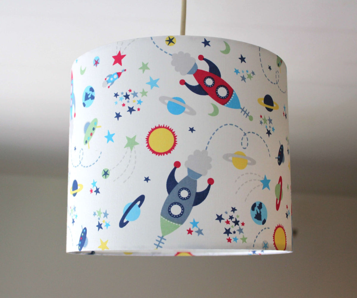 Children's lampshade with space-themed design featuring planets, rockets, sun, stars, and galaxy on a plain background.