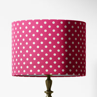 Bright pink lampshade with white polka dots on a white background.