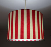 Modern striped bright red and white ceiling drum lampshade on a dark background.