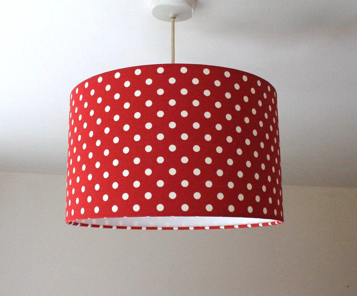 Bright red lampshade with white polka dots hanging against a plain background.