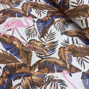 Upholstery fabric with pink flamingo and brown leaves pattern on a white background.
