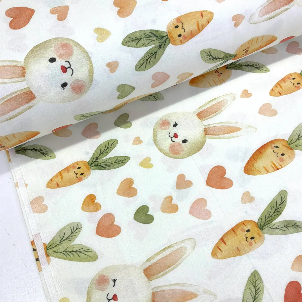 100% cotton fabric featuring kawaii bunny faces, smiling orange carrots with green leaves and pastel hearts on a white background.