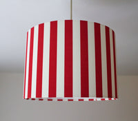 Red and white striped ceiling lampshade hanging on a plain background.