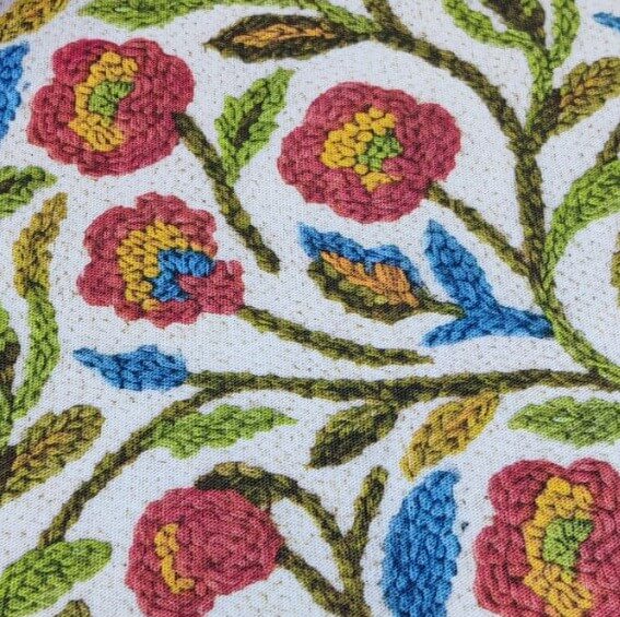 Embroidery patterned floral upholstery fabric in burgundy red, mustard yellow, blue, green and white.