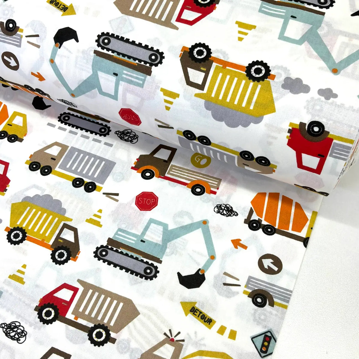 Colourful 100% cotton fabric featuring construction vehicles including diggers, dump trucks, cement mixers, excavators and lorries on a white background.