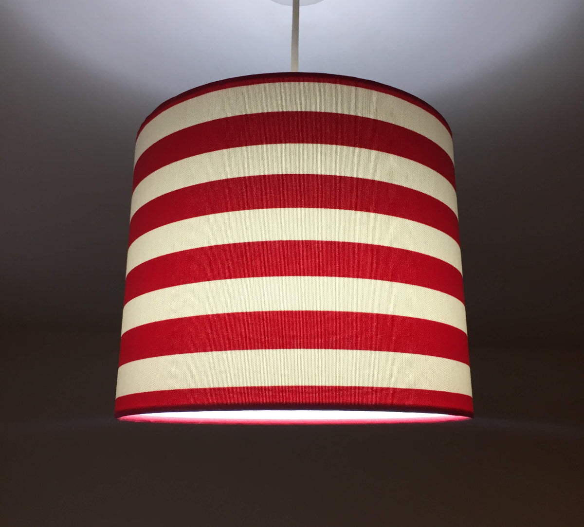 Bright red and white horizontal striped lampshade on a dark background.