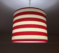 Bright red and white horizontal striped lampshade on a dark background.