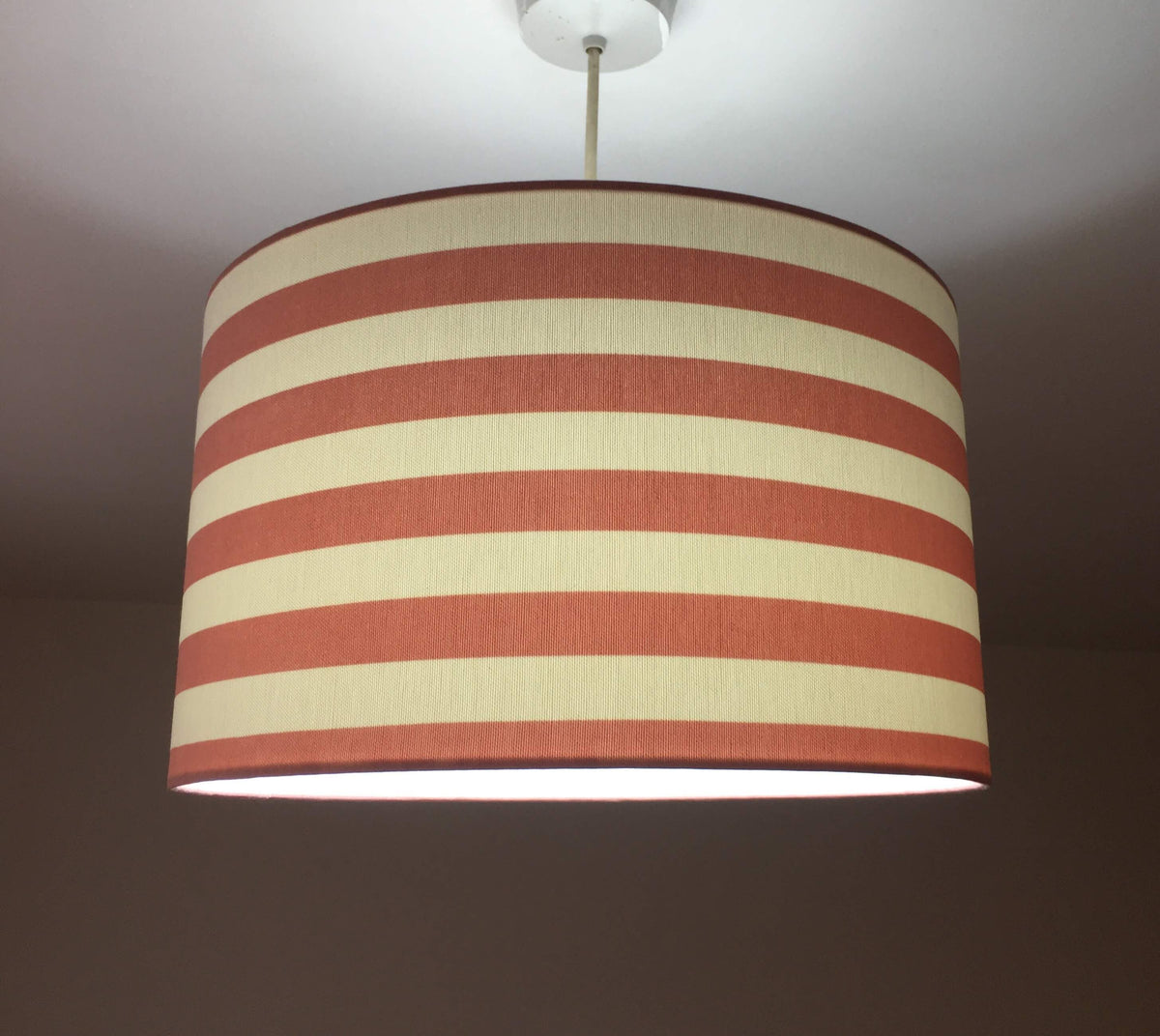 Horizontal stripe lampshade with red and white pattern on a plain background.