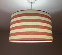 Horizontal stripe lampshade with red and white pattern on a plain background.