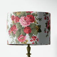 Red pink floral and sage green leaves patterned lampshade on a white background.