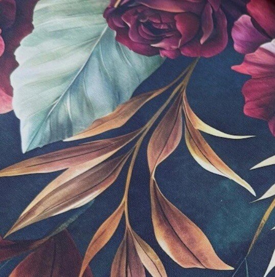 Close up of earthy leaves and burgundy flowers patterned fabric.