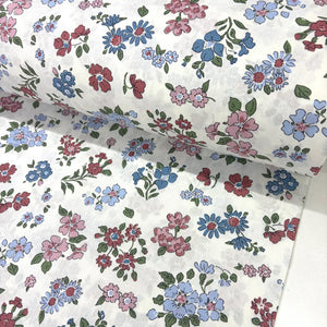 Ditsy floral cotton fabric patterned with blush pink, burgundy and blue flowers on a white background.