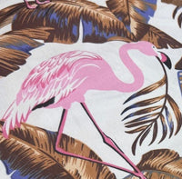 Tropical fabric pattern with pink flamingo and palm leaves.