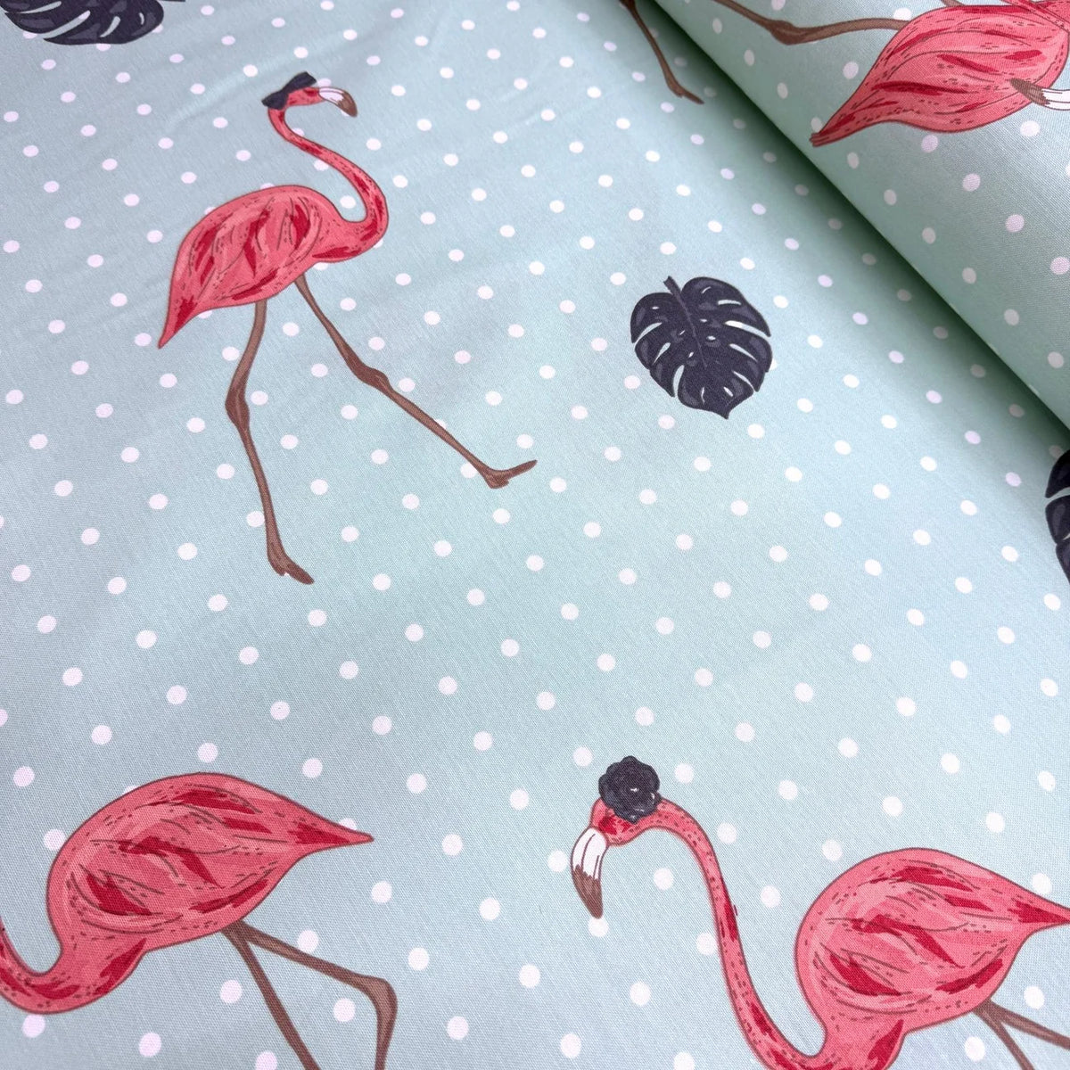 Pink flamingo pattern on a light blue upholstery fabric with white polka dots.