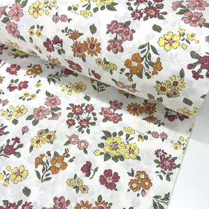 Floral cotton fabric patterned with blush pink, terracotta, yellow and burgundy flowers on a white background.