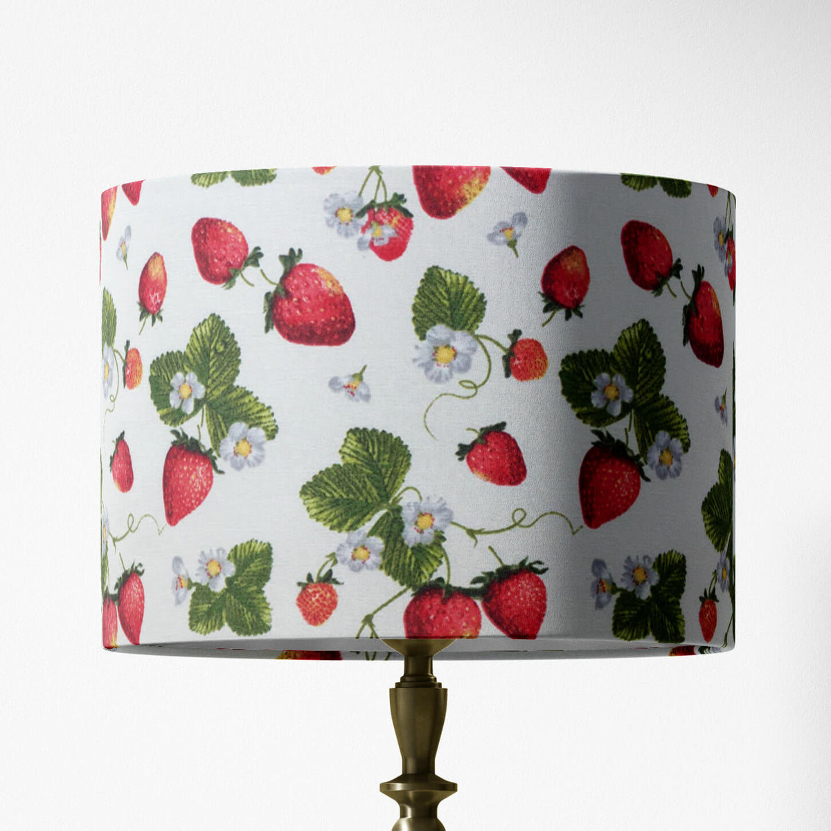 Table lampshade with white strawberry flower, red fruit and green leaves pattern on a white background.