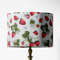Table lampshade with white strawberry flower, red fruit and green leaves pattern on a white background.