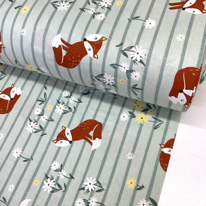 Cotton poplin fabric with fox and floral pattern on sage green striped background.