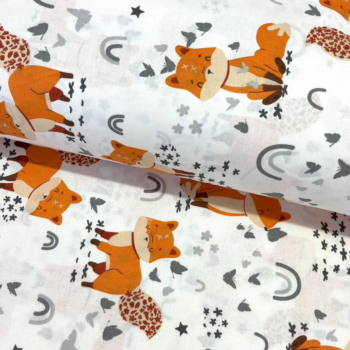 Fox print cotton fabric by the metre featuring orange woodland foxes, grey butterflies, flowers, stars and rainbows on a white background.