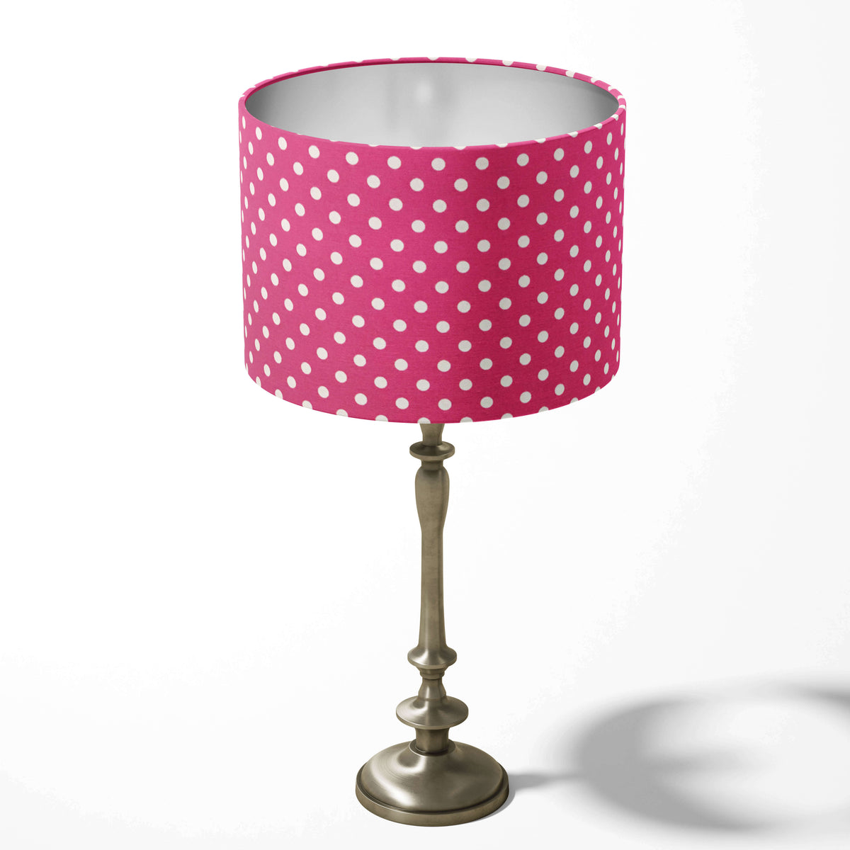 Hot pink table lampshade patterned with white polka dots on a white background.