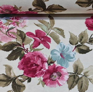 Close-up of floral fabric with pink and blue flowers and sage green leaves on a white background.