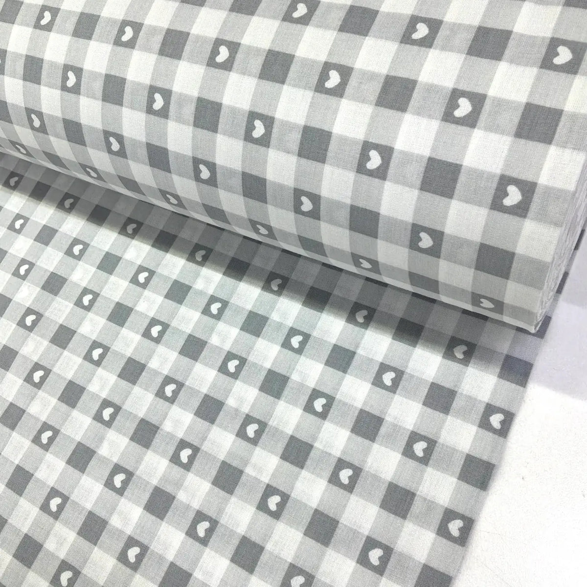 Grey cotton gingham fabric with white heart print, featuring a classic check pattern, ideal for dressmaking, quilting, patchwork and craft projects.