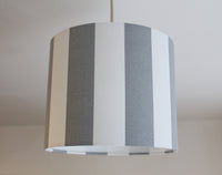 Striped ceiling lampshade with gray and white pattern on a plain background.