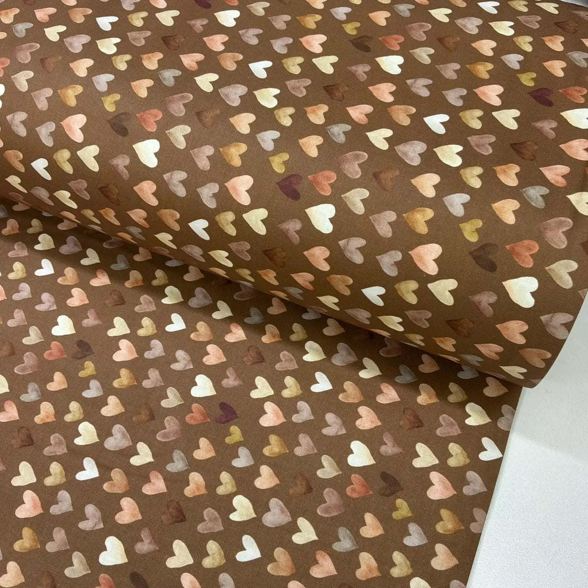 Brown neutral cotton fabric with an all-over heart print in cream, blush pink, beige and caramel.