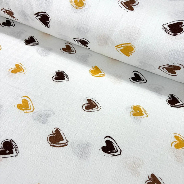 White muslin double gauze fabric with brown and mustard yellow heart patterns.