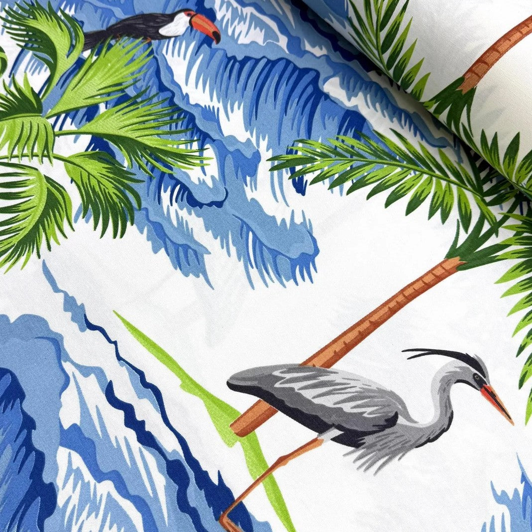 Tropical upholstery fabric with exotic birds, palm trees, and blue waves on a white background.