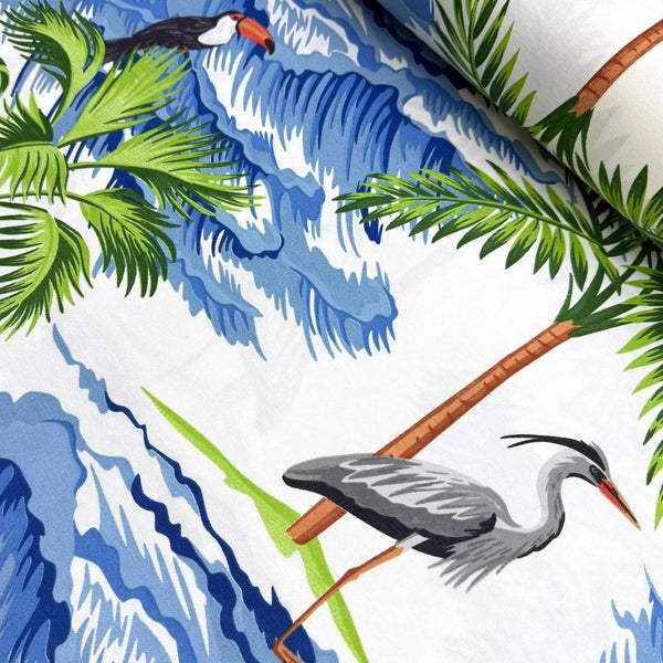 Tropical upholstery fabric with exotic birds, palm trees, and blue waves on a white background.