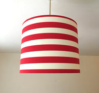 Striped red and white ceiling lampshade hanging against a plain background.