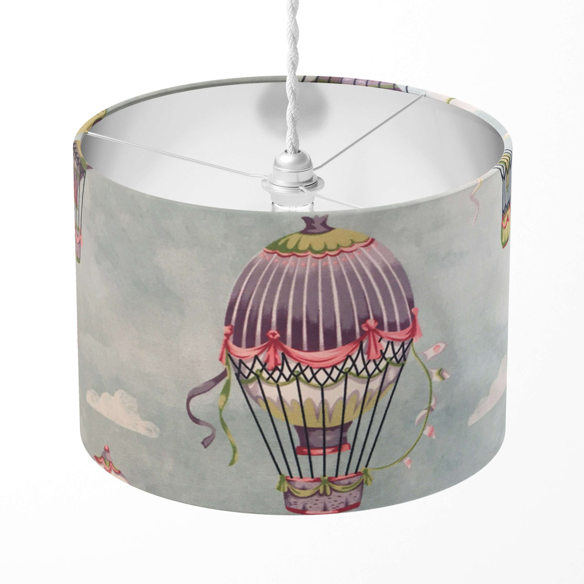 A drum lampshade with a baby blue colour featuring a hot air balloon design with a patterned border.