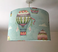 Sky blue drum lampshade with hot air balloon design hanging from a ceiling.